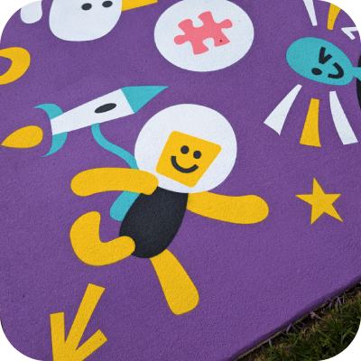 A brightly coloured path with a simply illustrated astronaut, rocket, alien, star and puzzle piece.