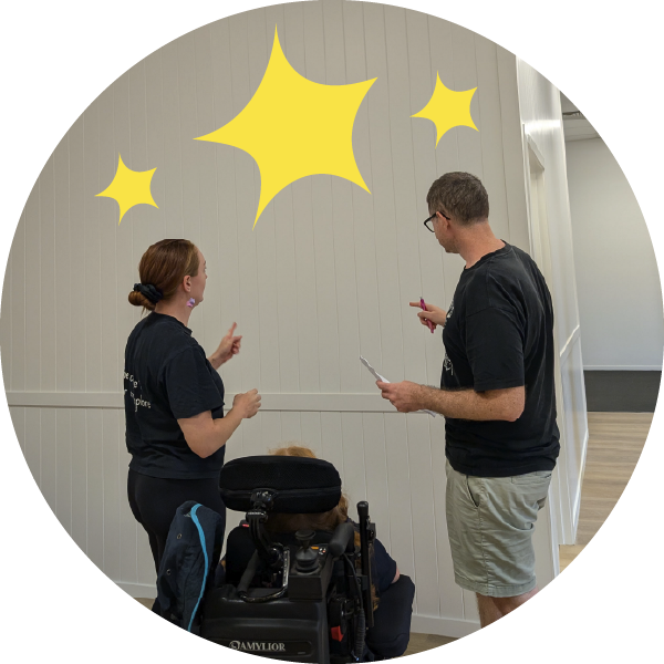 A man, lady and child in a wheelchair discuss designs for a wall.