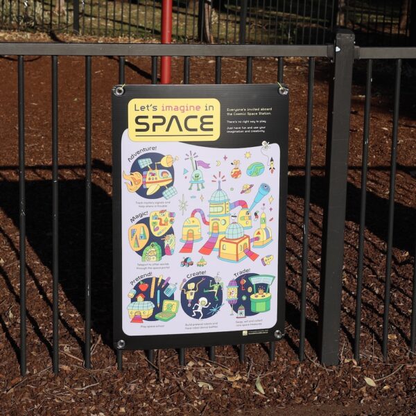 Inclusive imaginary play poster on a fence showing a colourful space station with playful prompts for play.